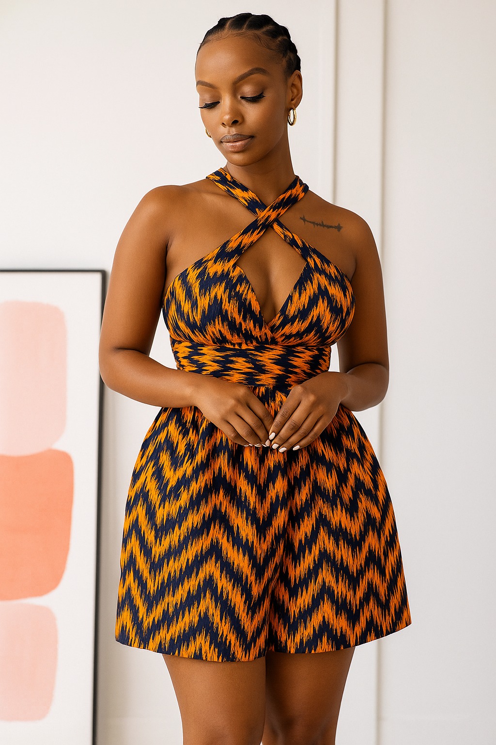 The Kora Sunset Playsuit: burnt-orange and indigo chevron weave, halter straps crossed at the throat