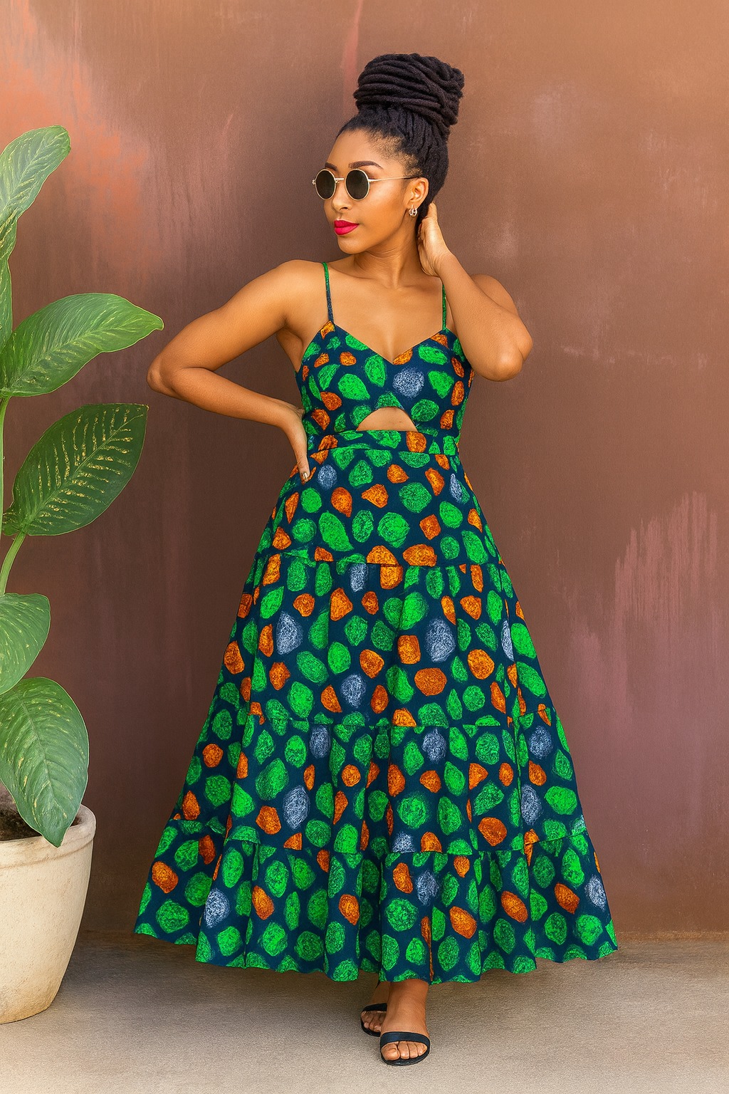 Selene Maxi in forest-stone: green, amber and slate pebble batik on dark teal against a rust wall